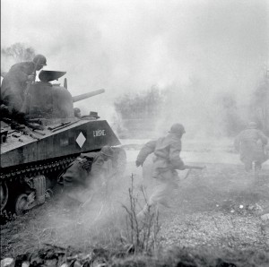 Les nouvelles recrues FFI incorporées dans la 1re armée française s'entraînent à accompagner les chars.  L'infanterie portée saute du char en marche et va franchir le ruisseau, protégée par un écran fumigène, Alsace, 1er-12 mars 1945 © ECPAD / Jacques Belin