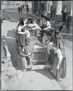 Jeunes Alsaciennes en costume traditionnel autour d'une jeep du service Presse Cinéma du SCA. D'après la légende d'origine, elles sont en train de lire une carte les noms des villes libérées, Alsace, 18 mars 1945 © ECPAD / Jacques Belin